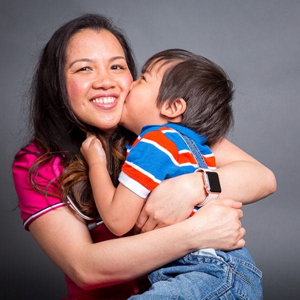 Woman holding a little boy who is kissing her cheek