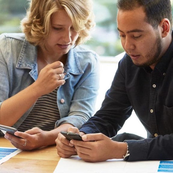 Two people comparing items on mobile phones