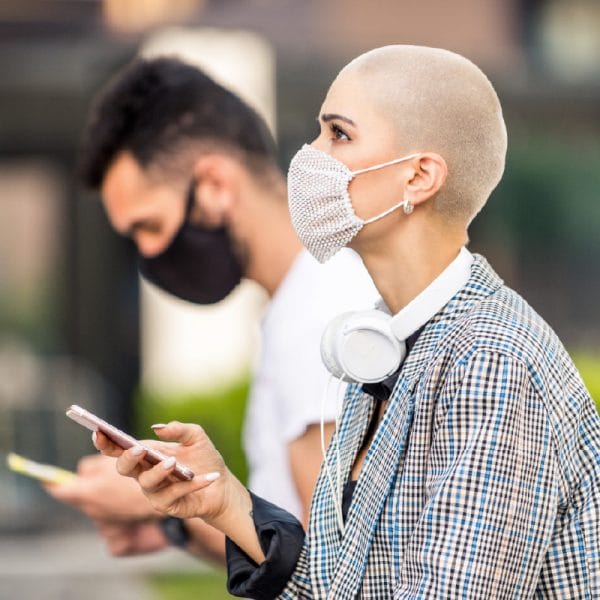 Young person in the foreground looking up, holding a mobile phone